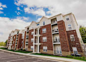 Thumbnail 34 of 36 - A large apartment building with a parking lot in front.