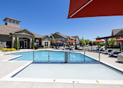 Thumbnail 1 of 21 - A large swimming pool in front of a building with a red umbrella.