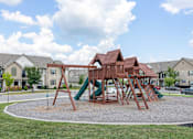 Thumbnail 4 of 21 - A playground with a green slide and a brown wooden structure.