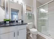 Thumbnail 20 of 21 - A bathroom with a white toilet and a glass shower stall.