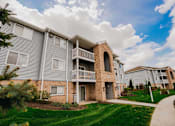 Thumbnail 3 of 42 - A residential building with a balcony and a small garden in front.