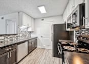 Thumbnail 8 of 42 - A kitchen with a black refrigerator and wooden floors.