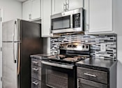 Thumbnail 9 of 42 - A kitchen with a black refrigerator, black stove, and black oven.