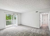 Thumbnail 11 of 42 - A sparsely furnished room with a carpeted floor and a sliding glass door leading to a balcony.