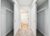 Thumbnail 15 of 42 - A hallway with white walls and a carpeted floor.