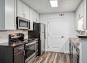 Thumbnail 17 of 42 - A kitchen with a black stove top oven and a black refrigerator.