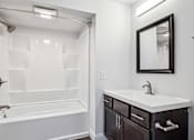 Thumbnail 23 of 42 - A white bathroom with a black framed mirror.