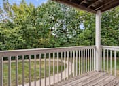 Thumbnail 28 of 42 - A wooden deck with a white railing overlooks a grassy area.