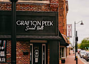 Thumbnail 41 of 42 - The Grafton Peek Social Hall is a brick building with a black awning.
