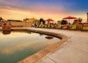 Thumbnail 25 of 25 - A pool surrounded by red umbrellas and lounge chairs.