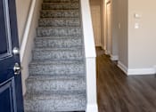Thumbnail 11 of 27 - A staircase with a blue door on the left and wooden flooring.