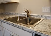Thumbnail 5 of 27 - A kitchen sink with a faucet and a granite countertop.