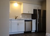 Thumbnail 9 of 27 - A kitchen with white cabinets and a black refrigerator.
