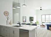 Thumbnail 11 of 17 - A modern kitchen with a large island and a bedroom in the background.