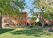 Thumbnail 4 of 16 - A large red brick building with a tree in front of it.
