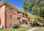 Thumbnail 2 of 16 - A red brick building with a tree in front.