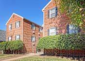 Thumbnail 1 of 15 - A red brick building with green bushes in front.