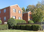Thumbnail 3 of 15 - A red brick building with a black fence in front.