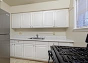 Thumbnail 13 of 15 - A kitchen with white cabinets and a black stove top.