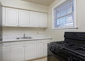 Thumbnail 12 of 15 - A kitchen with white cabinets and a black stove top oven.