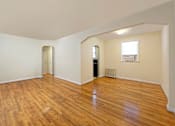 Thumbnail 6 of 15 - A room with wooden floors and white walls.