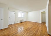Thumbnail 8 of 15 - A room with wooden floors and white walls.