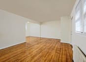 Thumbnail 7 of 15 - A room with wooden flooring and white walls.
