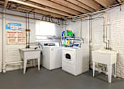 Thumbnail 15 of 15 - A laundry room with a washer and dryer, sink, and a sign on the wall.