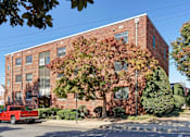 Thumbnail 1 of 18 - A red truck is parked on the street in front of a brick building.