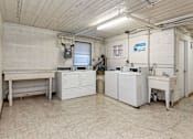 Thumbnail 17 of 18 - A clean, white industrial room with a table, cabinets, and a machine.