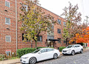 Thumbnail 5 of 15 - Two cars parked in front of a brick building.