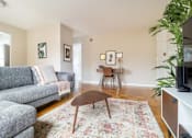 Thumbnail 7 of 16 - A living room with a grey couch and a wooden coffee table.