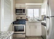 Thumbnail 11 of 16 - A kitchen with a stove, oven, microwave, and refrigerator.