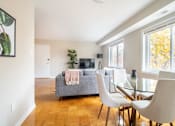 Thumbnail 8 of 16 - A room with a grey couch, a glass table, and a white dining chairs.