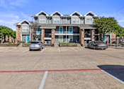 Thumbnail 10 of 42 - A parking lot in front of a multi-story apartment building.