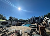 Thumbnail 40 of 42 - A sunny day at the Fairway pool area with chairs and tables arranged for relaxation.