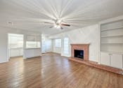 Thumbnail 2 of 18 - A large, empty room with a fireplace and wooden floors.
