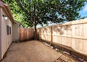 Thumbnail 8 of 18 - A backyard with a wooden fence and a tree.