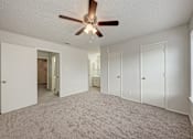 Thumbnail 5 of 18 - A room with a ceiling fan and carpeted floor.