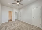 Thumbnail 11 of 18 - A room with a ceiling fan and carpeted floor.