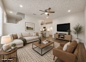 Thumbnail 9 of 18 - A living room with a white couch, a coffee table, and a television.