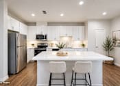 Thumbnail 10 of 18 - A kitchen with white cabinets and a white island with two chairs.