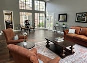 Thumbnail 34 of 36 - A living room with brown leather furniture and a large window.