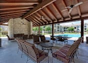 Thumbnail 9 of 21 - A patio with a table and chairs and a pool in the background.