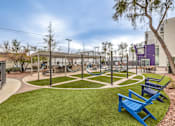 Thumbnail 6 of 14 - A park with a blue bench and a green lawn.