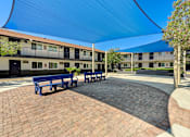 Thumbnail 15 of 28 - A courtyard with benches and a building in the background.
