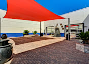 Thumbnail 10 of 28 - A red shade structure is over a brick walkway.