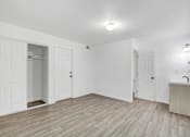 Thumbnail 8 of 56 - A room with white walls and wooden flooring, featuring a door, a window, and a light fixture.