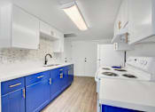 Thumbnail 1 of 56 - A kitchen with blue cabinets and a white stove top oven.