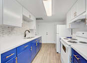Thumbnail 4 of 56 - A kitchen with white and blue cabinets and appliances.